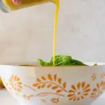 Honey Dijon Vinaigrette being poured over spinach