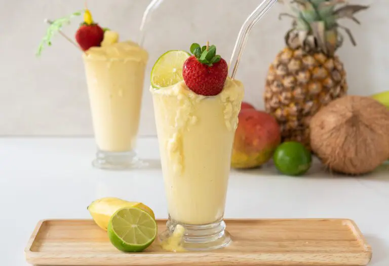 Pineapple, Coconut and Lime Blended in Tall Glass with a tray of fresh summer fruit