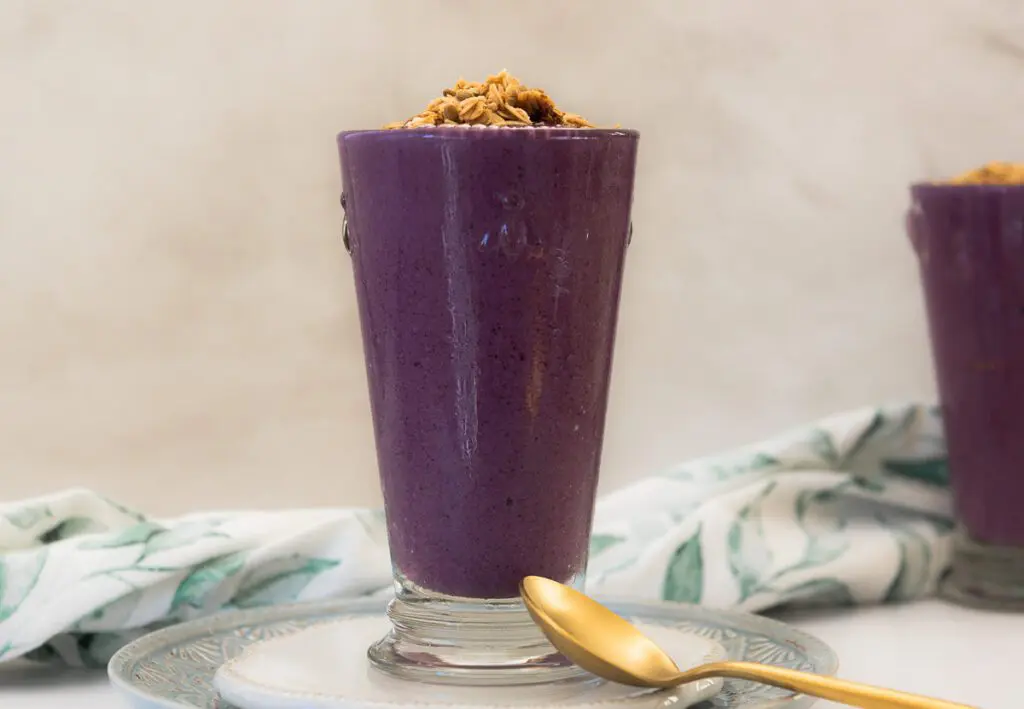 Glass of healthy blueberry smoothie with a gold spoon