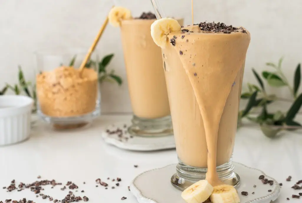 Pouring PB2 Smoothie into a glass with powdered peanut butter