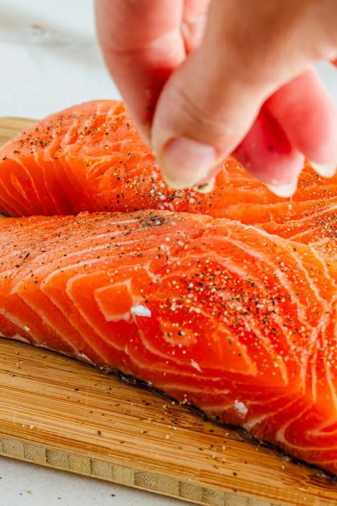 Season salmon with salt and pepper
