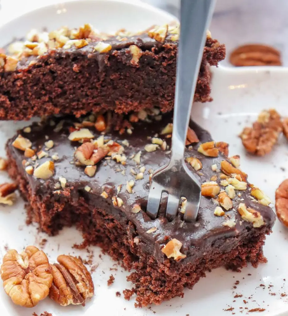 Piece of gluten free chocolate cake with chocolate frosting and pecans