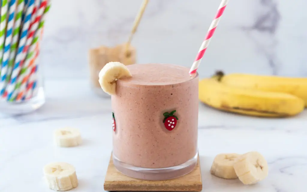 glass of pink strawberry PB2 Powder Smoothie with striped straw
