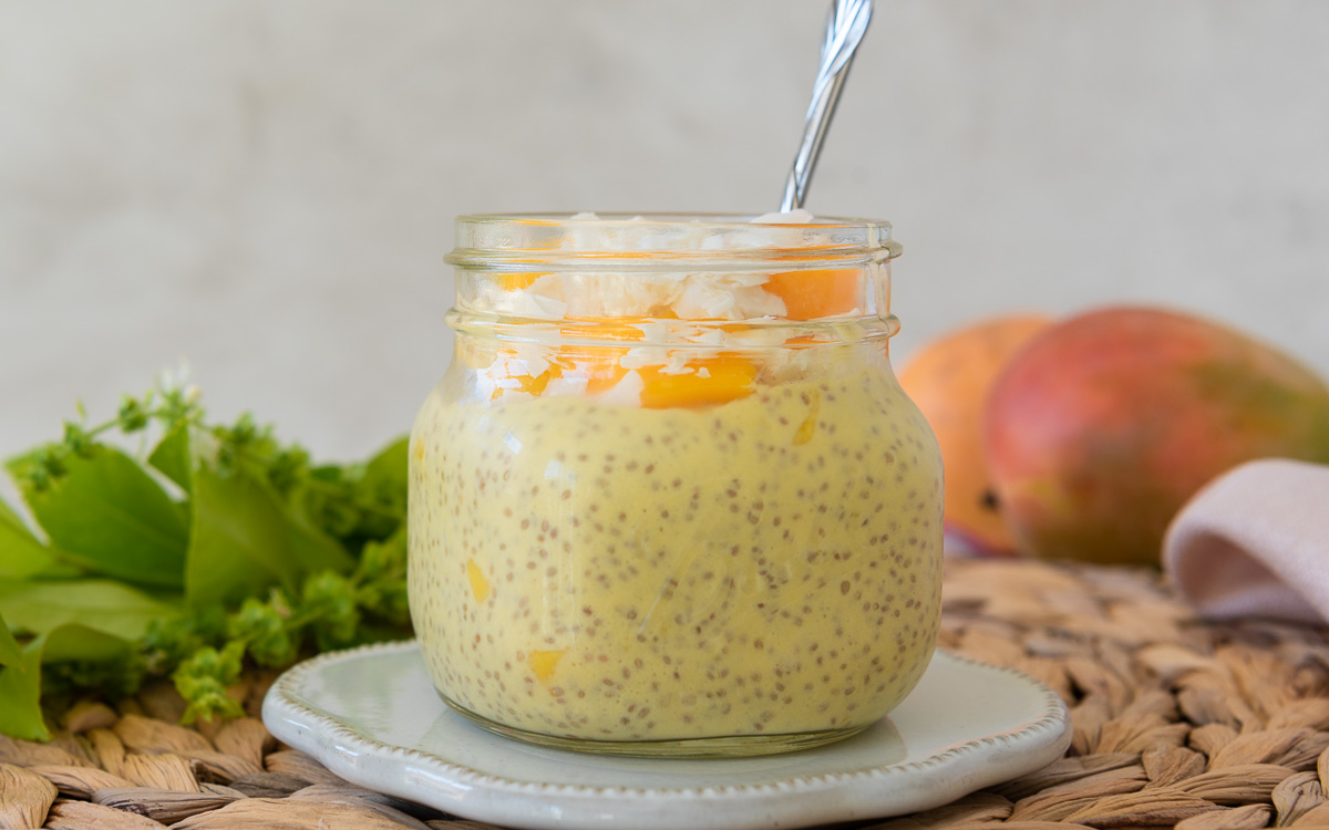 Mango Chia Pudding in a Glass jar with fresh fruit and mangoes