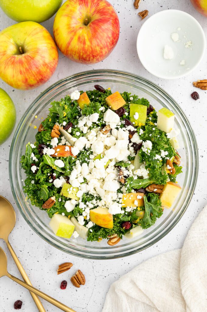 Feta Cheese on Salad in Glass Bowl surrounded by apples. 
