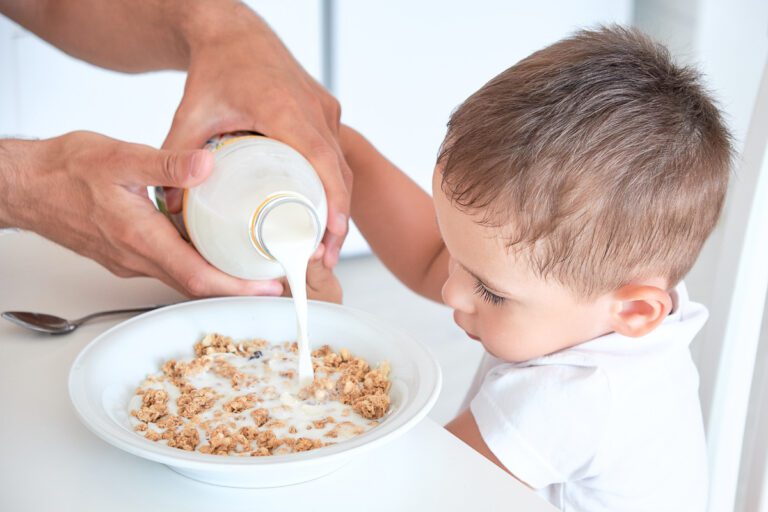 Hands pouring milk into cereal