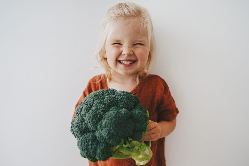 Child holding a huge head of broccoli 