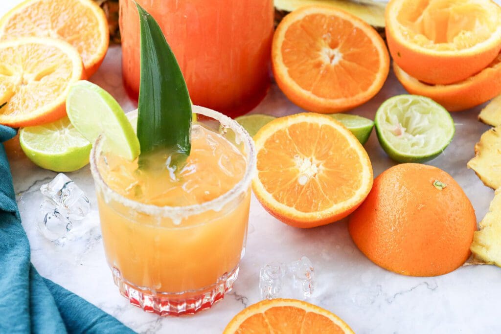 Glass of Sunrise Mocktail surrounded by fresh oranges 