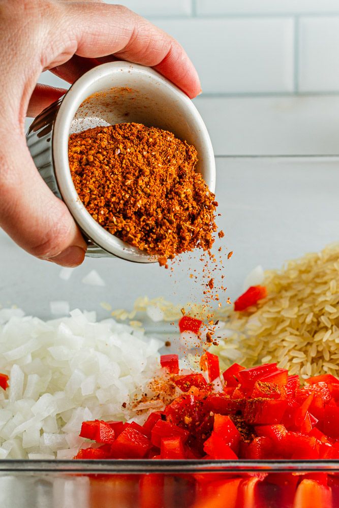 adding spices to mexican casserole pan 